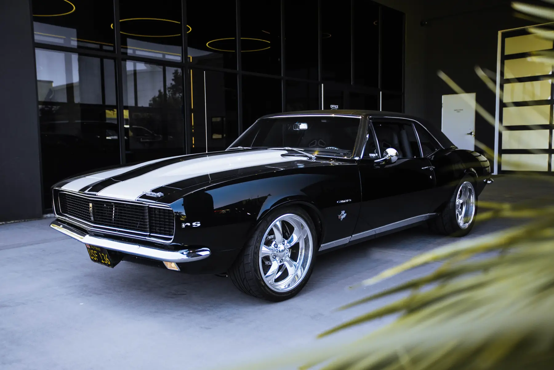 Black muscle car rolling out of the Kreations Auto Body showroom
