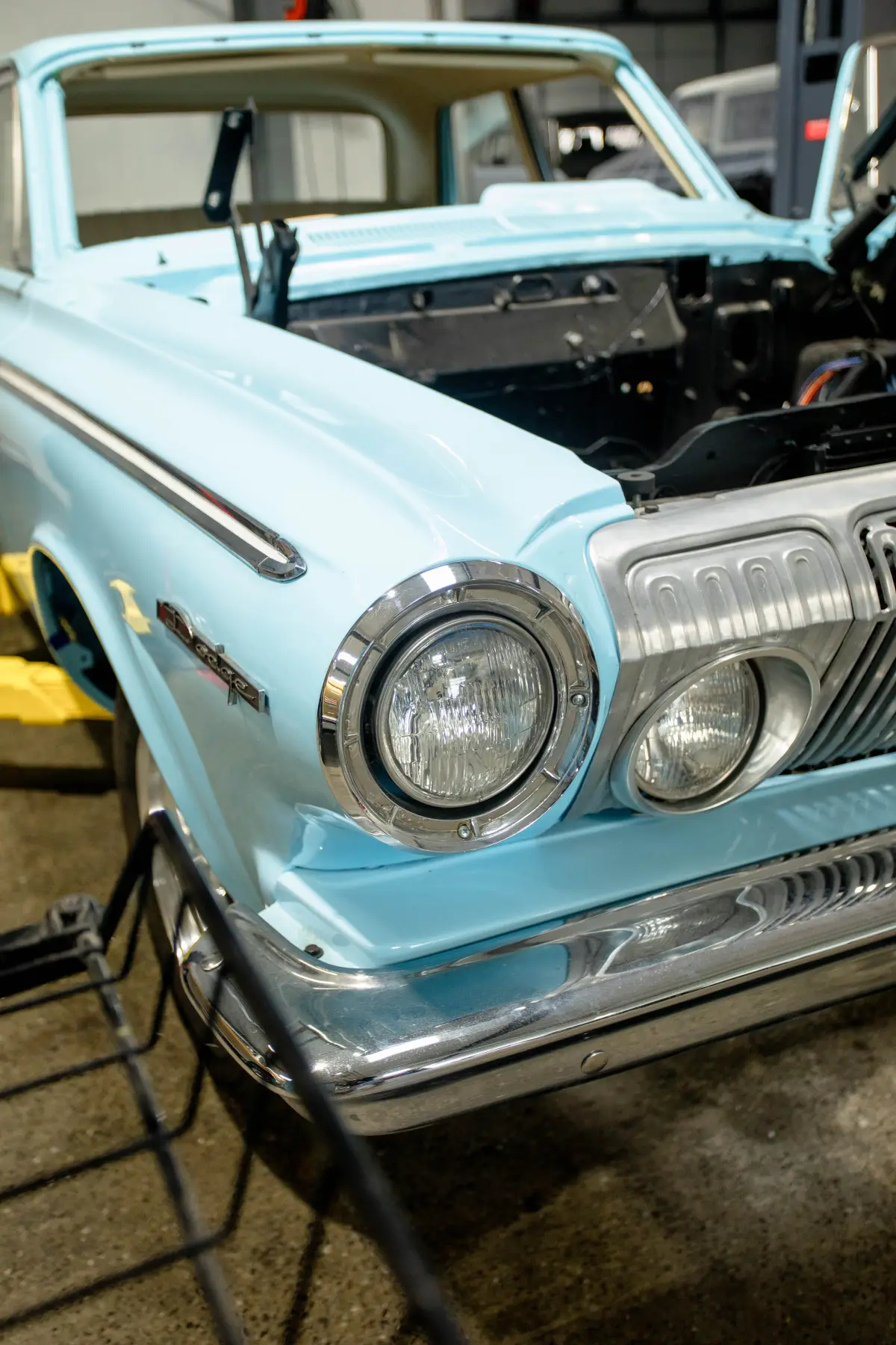 Chrome headlight and grille on a light-blue classic at Kreations Auto Body